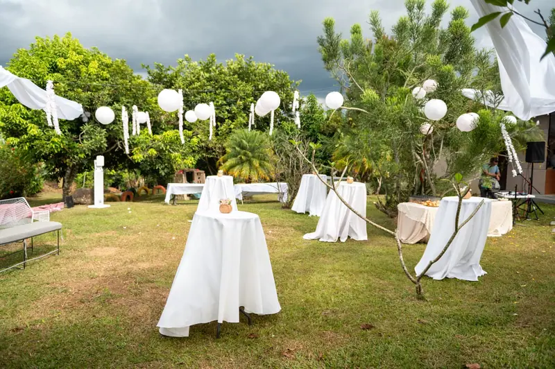 Cóctel al aire libre con mesas altas y lámparas blancas